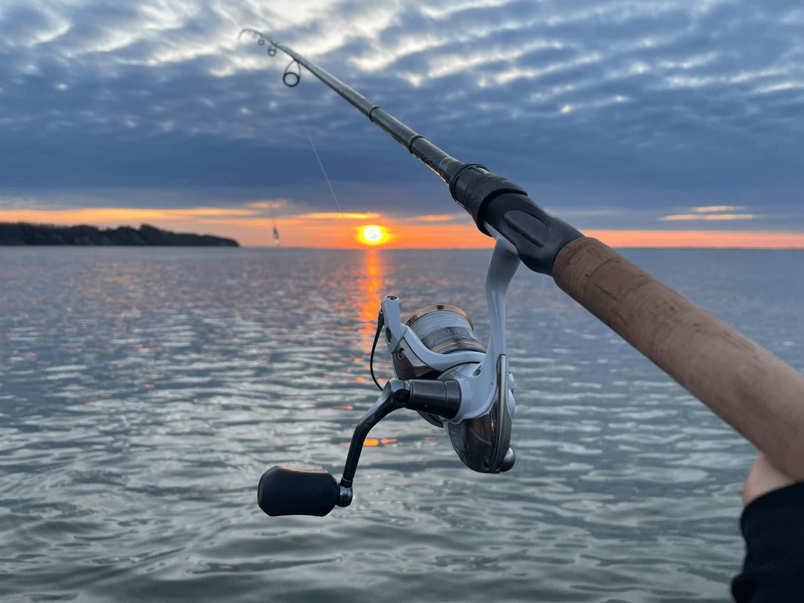Angler mit Rute an der Ostseeküste bei Sonnenuntergang