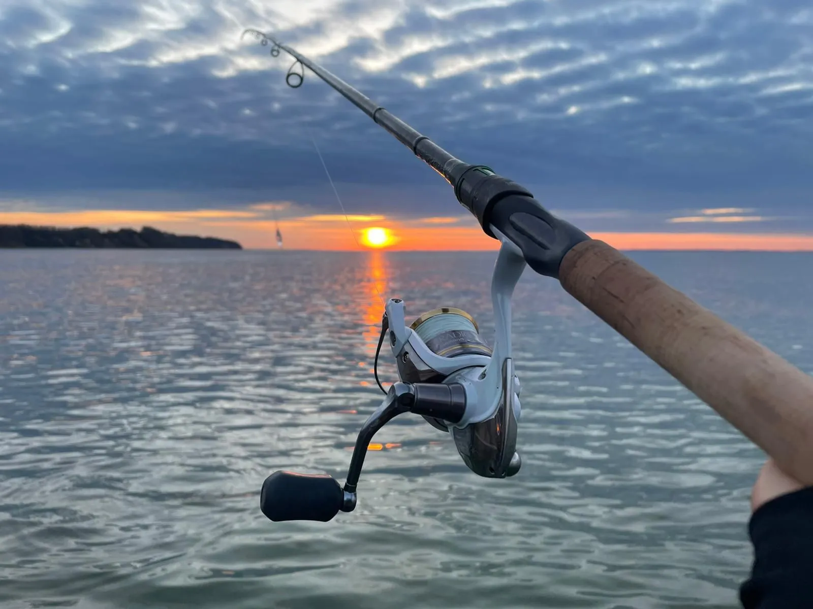 Angler mit Rute an der Ostseeküste bei Sonnenuntergang